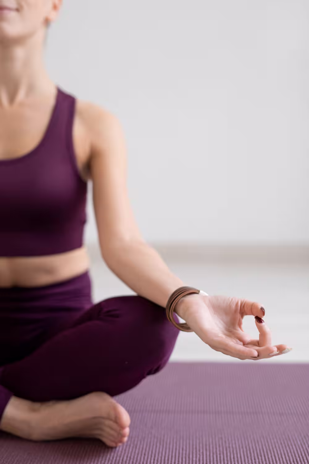 Woman meditating in yoga pose; reflects centered mind, mind-body mastery, and elite status.